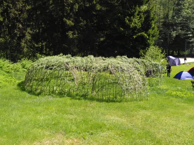 runder Weidentunnel, schneckenförmig auf einer Wiese am Waldrand im Frühling